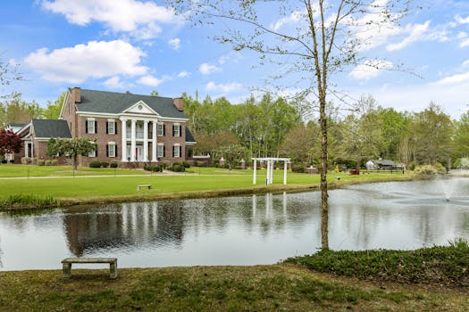 Beautiful colonial-style house with a pond in Sims, NC, showcasing classic architecture and serene surroundings.